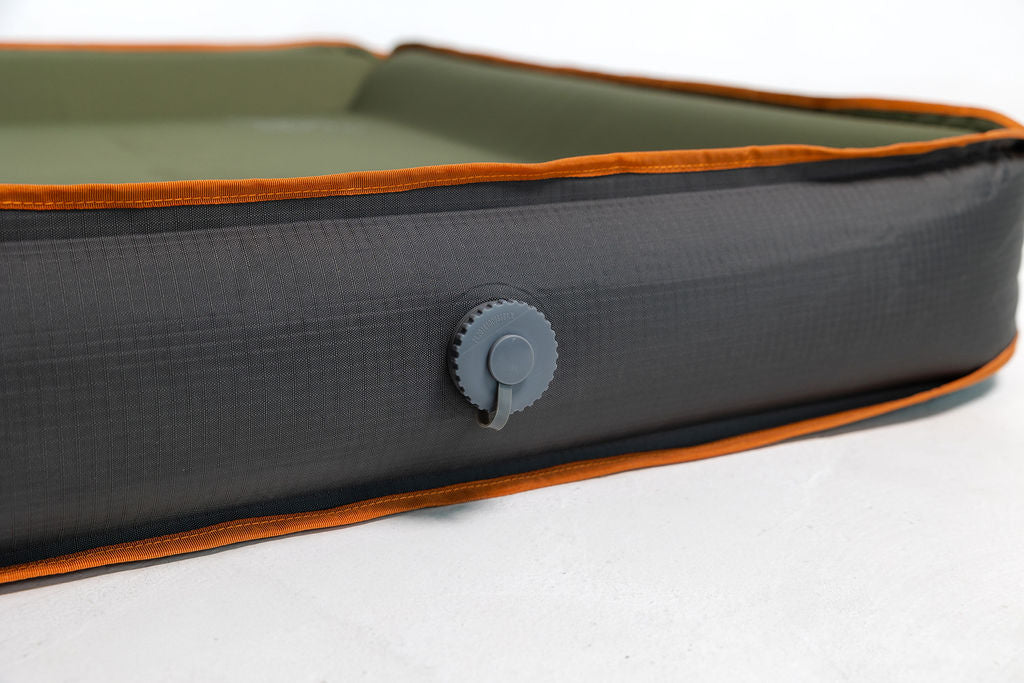 A self inflating travel dog bed with a green, orange, and grey color scheme, featuring one way inflating valve.